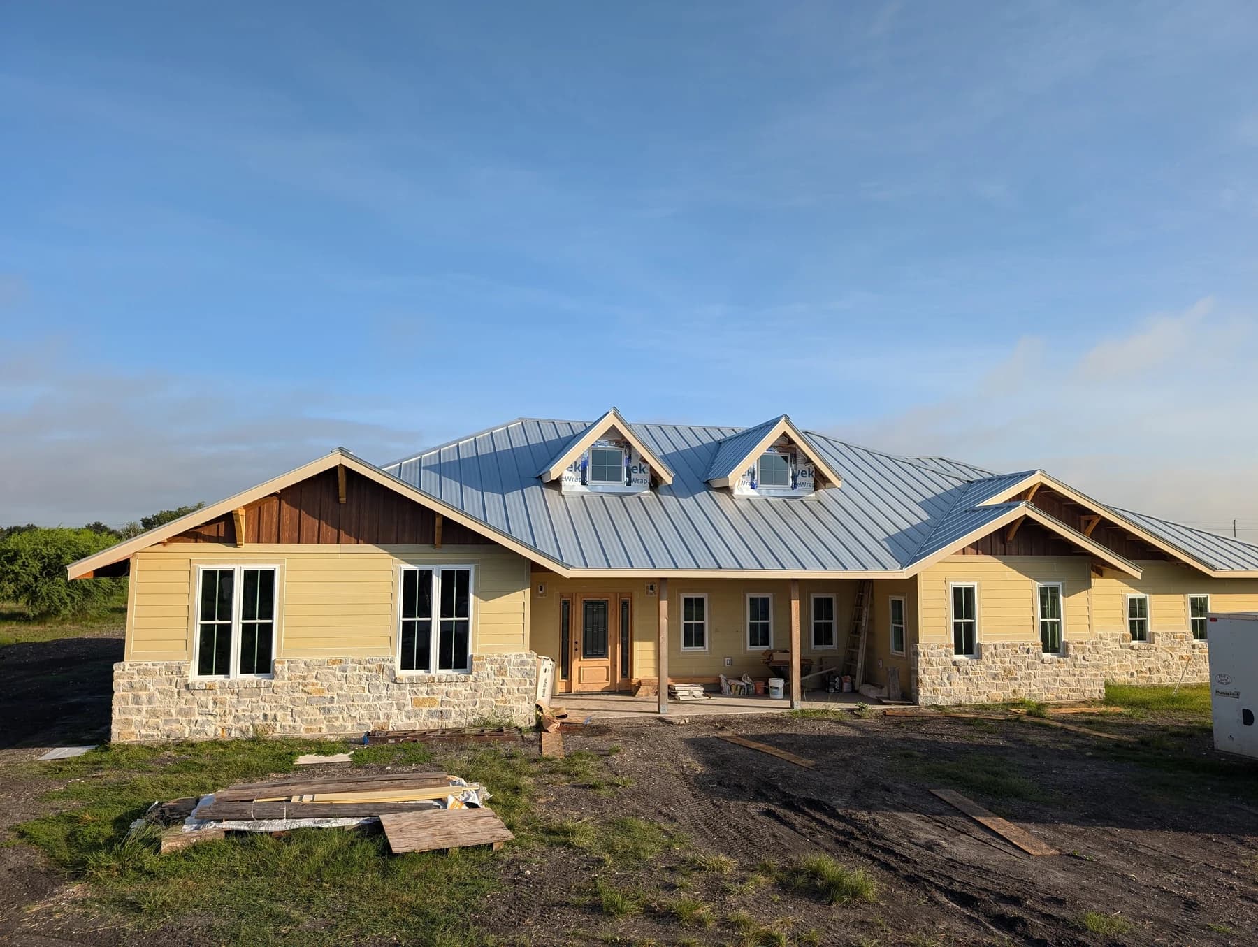 The Charleston front elevation during construction, with stonework and roof installed and siding awaiting its blue finish