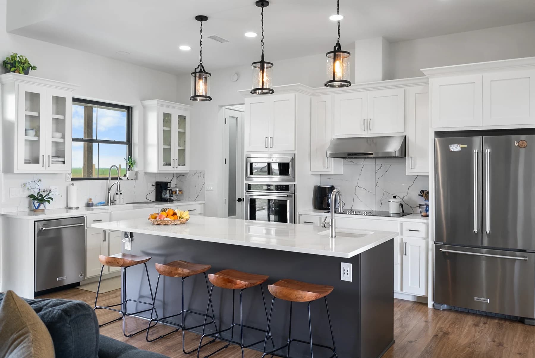The finished Plymouth kitchen with a generous island, white cabinetry and lantern pendants