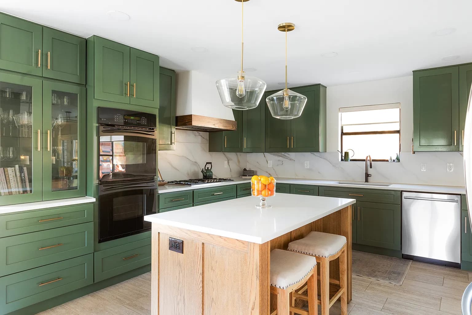 Green kitchen cabinetry, range and wood island in the finished Provence remodel